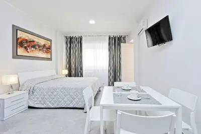 a white bedroom with a bed and a table with chairs at Valery Guest House in Rome