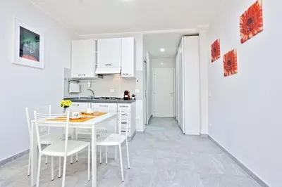 a white kitchen with a white table and chairs at Valery Guest House in Rome
