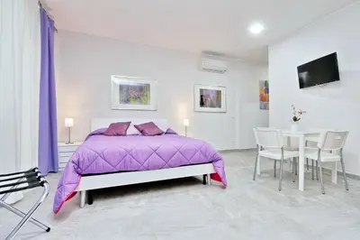 a bedroom with a purple bed and a table and chairs at Valery Guest House in Rome