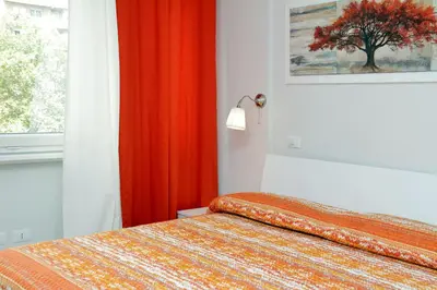 a bedroom with a bed with an orange curtain and a window at Valery Guest House in Rome