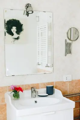 a bathroom sink with a mirror and a vase of flowers at Xystum in Rome