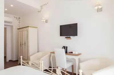 a living room with white furniture and a tv on the wall at Donna Margherita Rome Suite & Rooms in Rome