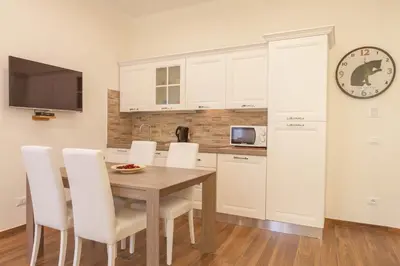 a kitchen with a table and white cabinets and a clock at Donna Margherita Rome Suite & Rooms in Rome
