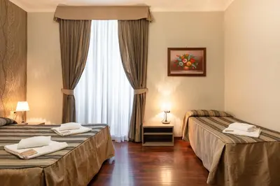 a hotel room with two beds and a window at Dreams Roma B&B in Rome