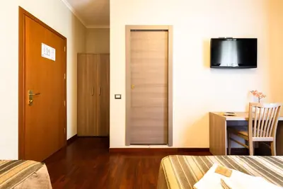 a room with a bed and a desk and a door at Dreams Roma B&B in Rome