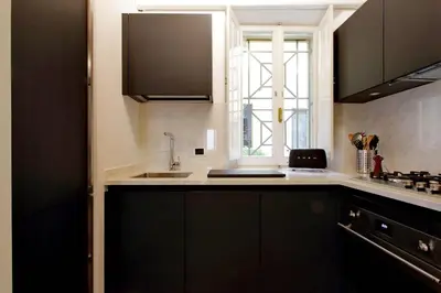 a kitchen with black cabinets and a sink and a window at YCH-Farnese Charme in Rome