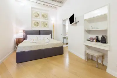 a white bedroom with a bed and a chair at StarHome Pantheon in Rome
