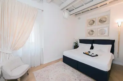 a white bedroom with a bed and a chair at StarHome Pantheon in Rome