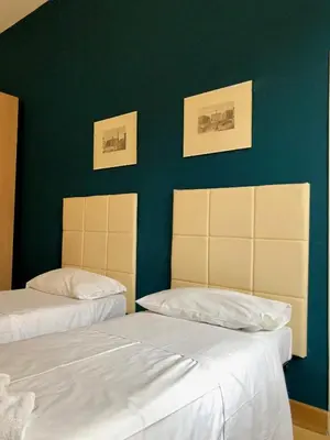 two beds in a room with a green wall at Monti Friendly Rome House in Rome