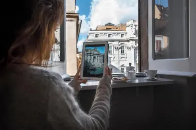 a woman taking a picture of a city on a tablet at Trevi Luxury Maison in Rome