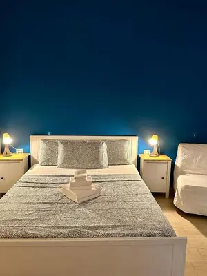 a bedroom with a bed with a blue wall at Romulea Guest House in Rome