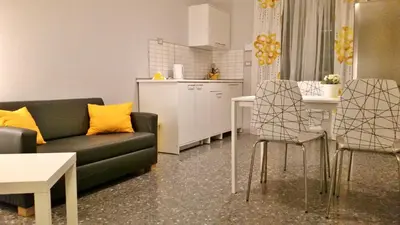 a living room with a couch and chairs and a kitchen at Romulea Guest House in Rome