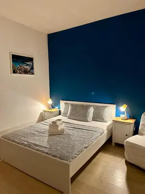 a bedroom with a large bed with a blue wall at Romulea Guest House in Rome
