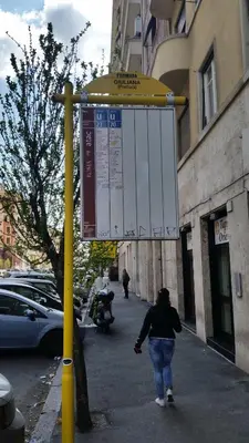 a woman walking down a sidewalk under a street sign at Jubilee 2 in Rome