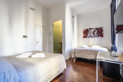 a bedroom with two beds and a desk and a mirror at Relais Incantesimo Vaticano in Rome