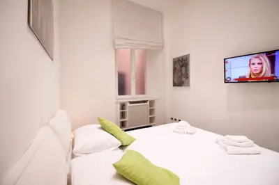 a white room with a bed and a tv on a wall at Spanish Steps Art Apartment in Rome