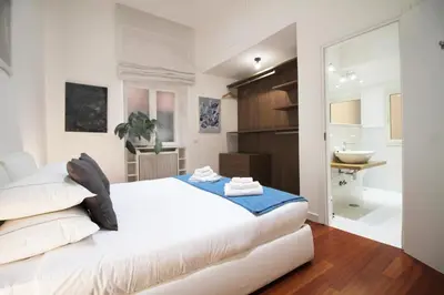 a bedroom with a white bed and a bathroom at Spanish Steps Art Apartment in Rome