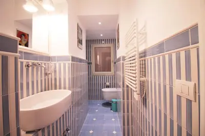a blue and white bathroom with a sink and a toilet at Spanish Steps Art Apartment in Rome