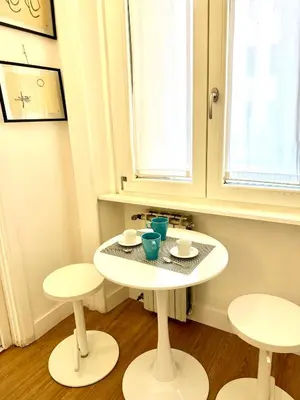 a small white table and two stools in a room at Angelico 90 in Rome