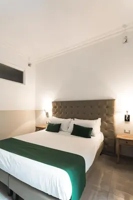 a bedroom with a large white bed with green accents at Vaticano Luxury Guest House in Rome