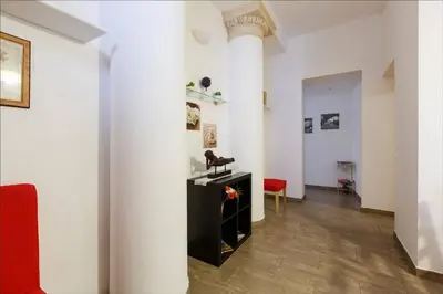 a room with white walls and a column and a red chair at Cuore di Testaccio Apartment in Rome