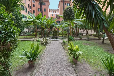 a garden with palm trees and a fountain at Vatican White Domus in Rome