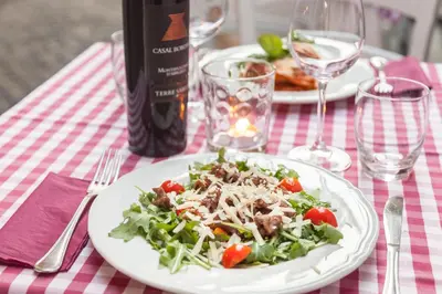 a plate of salad on a table with a bottle of wine at Casa in Monti in Rome