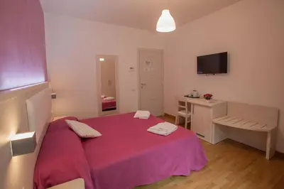 a bedroom with a pink bed and a desk at B&B Momenti Romani in Rome