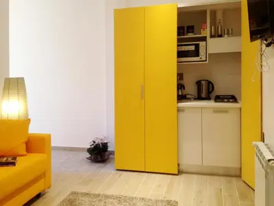 a yellow cabinet in a living room with a kitchen at The Pope At The Window in Rome