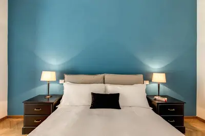 a bedroom with a blue wall and a bed with two lamps at YH SUITE 131 in Rome