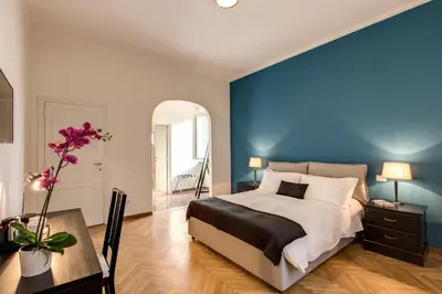 a bedroom with a blue wall and a bed and a table at YH SUITE 131 in Rome