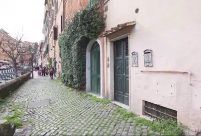 a cobblestone street next to a building with a green door at Garibaldi Roof Garden in Rome