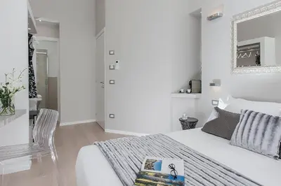 a white bedroom with a bed and a chair at Colosseum Corner in Rome