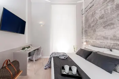 a white bedroom with a bed and a desk at Colosseum Corner in Rome