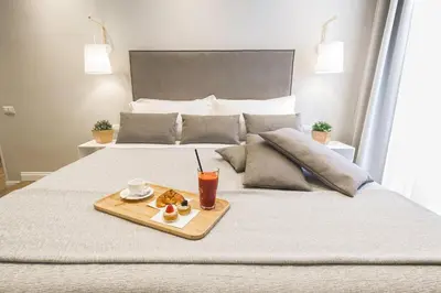 a tray of food and a drink on a bed at Colonna Luxury Suites in Rome