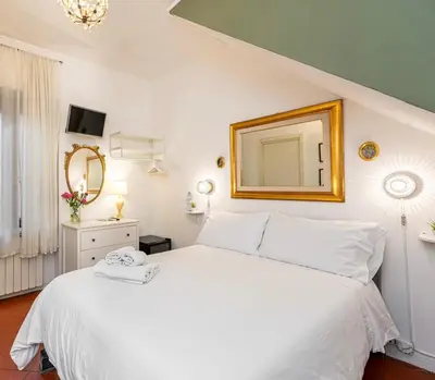 a bedroom with a white bed with a mirror on the wall at Al Ponte Del Papa B&B in Rome