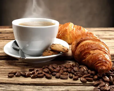 a cup of coffee and a croissant and coffee beans at Imperatore in Rome