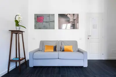 a blue couch with two orange pillows in a living room at Residenza Ottaviano 105 by Hili in Rome