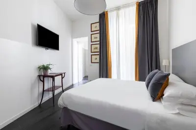 a hotel room with a white bed and a television at Residenza Ottaviano 105 by Hili in Rome