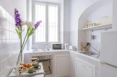 a white kitchen with a vase of flowers on a counter at Appartamento Castel Sant'Angelo in Rome