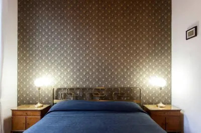 a bedroom with a blue bed and two nightstands with lamps at Sarah's House - Tourist Accommodation in Rome