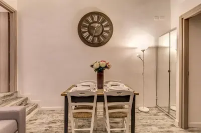 a table with chairs and a clock on the wall at Loft in San Pietro in Rome