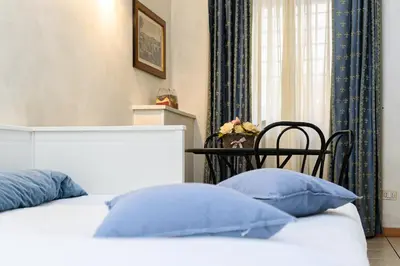 a bedroom with a bed with blue pillows and a chair at Apartment Julia Guesthouse Trevi - Spagna in Rome
