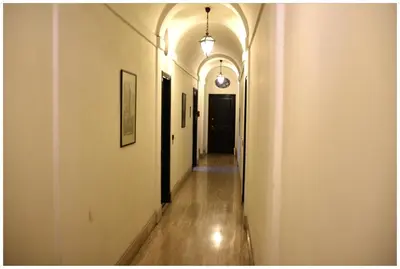 an empty hallway with white walls and wooden floors and a black door at Apartment Julia Guesthouse Trevi - Spagna in Rome