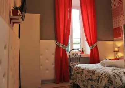 a bedroom with red curtains and a bed and a window at I Love Piramide in Rome