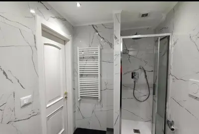 a bathroom with white marble walls and a shower at Vatican Apartment in Rome