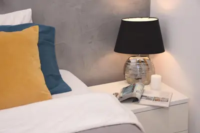a bed with a table with a lamp and a book at Rampa Brancaleone Apartment in Rome