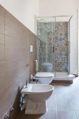 a bathroom with a toilet and a glass shower at G-House Pettinari in Rome