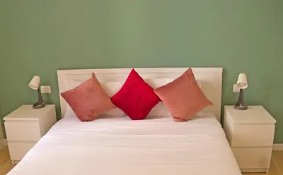 a bed with three red pillows on top of it at L'Esquilina Holiday House 2 in Rome