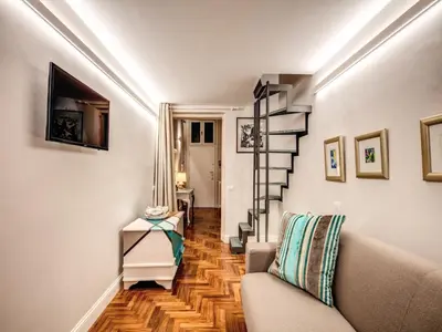 a living room with a couch and a spiral staircase at Residenza Paola - 2BR Trastevere in Rome